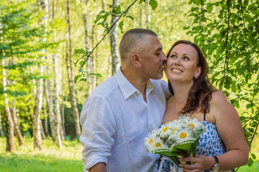 husband with wife and a bouquet of daisies in the Park