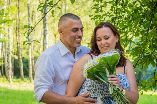 husband with wife and a bouquet of daisies in the Park