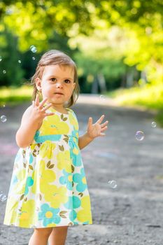 little girl catches bubbles in the Park