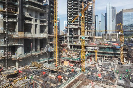 Laborers working on modern constraction site works in Dubai. Fast urban development consept.