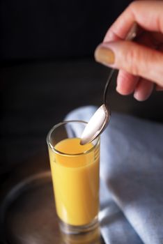 Egg liqueur  in the glass with spoon in the hand