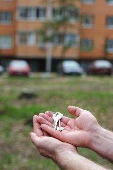 man holds keys to apartment on a background of multi-storey houses. concept