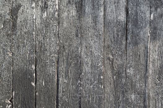 Background landscape oriented image of some vertical grunge black painted crackled and peeling silver grey weathered barn boards.