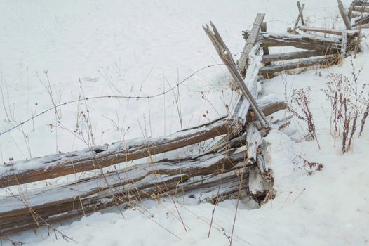 Wintery snow background of a split rail cedar fence with a sprinkle of snow,