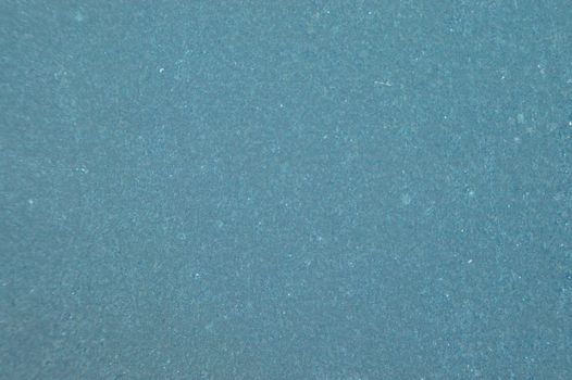Early morning frost on a windshield gives an even, grainy greeny blue background with some white flecks.