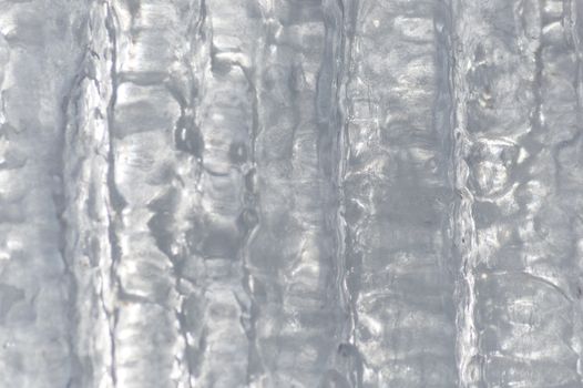 Ice background made of a number of icicles completely joined together. It has vertical patterns in the sunlight ice.