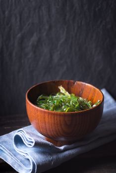 Chuka salad  in the wooden bowl  on the dark background vertical