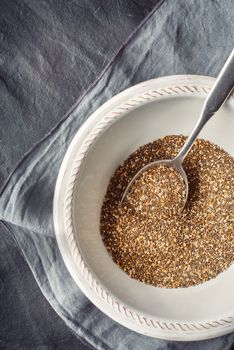 Chia seeds  in the white plate  with spoon on the dark stone table vertical