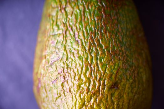 Avocado with relief peel on the purple background