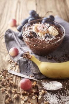 Chocolate chia pudding with fruit in the glass bowl on the wooden table