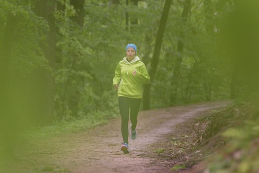 Sporty young female runner in forest.  Running woman. Female runner during outdoor workout in nature. Fitness model outdoors. Weight Loss. Healthy lifestyle. 