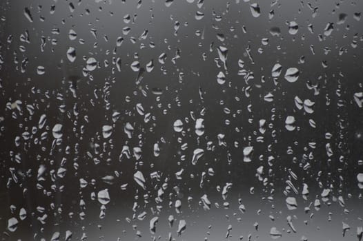 The image shows the pane only and  background is darker and the raindrops lighter.   The rain drops are even over the glass