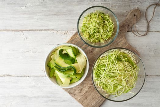 Raw zucchini noodles on the white wooden table top view