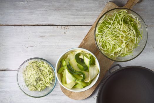 Raw zucchini noodles on the white wooden table