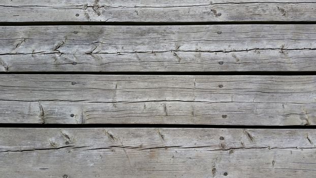 Silvery worn wood planks run horizonally as a background with character. Taken from above