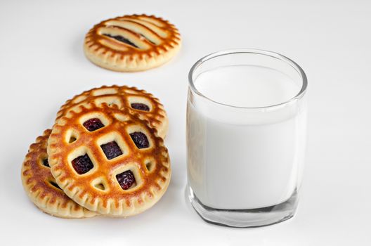 Cookies with filling and a glass of milk on a white surface
