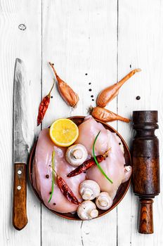 chicken raw fillets on kitchen plate with spices and mushrooms