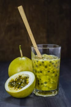 Fresh passion fruit juice in glass with passion fruits over wooden background , still life