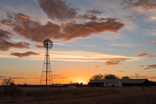 A water-pumping windmill at sunset on a farm near Ritchie in the Northern Cape Province of South Africa