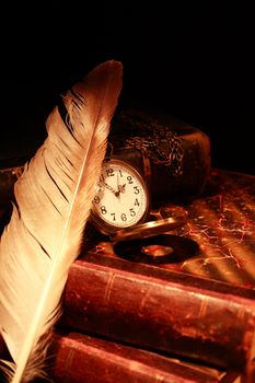 Vintage still life. Quill pen and pocket watch on old books