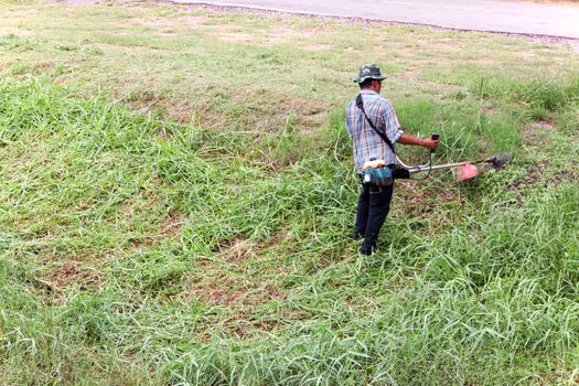 Worker cutting grass cutting machine with a small