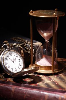 Vintage still life. Hourglass and pocket watch on old books