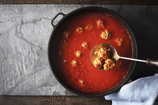 Meatball in the tomato sauce  in the pan on the stone background