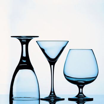 Three Various Empty Wine Glasses for Wine, Martini and Cognac with Reflection on Glass and Shadow Backlight. Blue Toned 