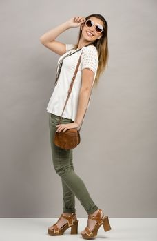 Beautiful young woman posing in front of a gray wall