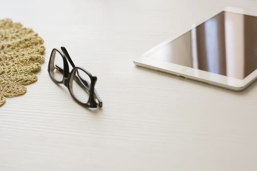 glasses and tablet on a white table