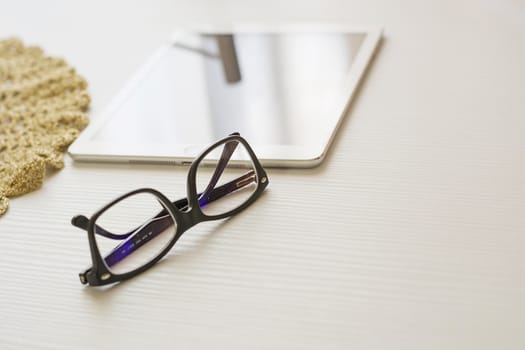 glasses and tablet on a white table