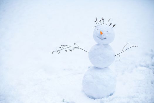Handmade smiling snowman standing in the snow