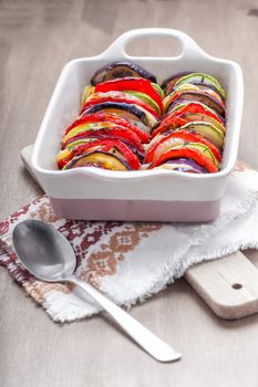 Tian vegetable casserole with spoon served on a table