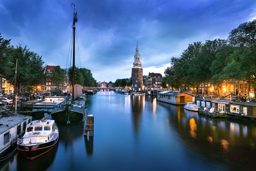 Beautiful night in Amsterdam. Night illumination of buildings and boats near the water in the canal.