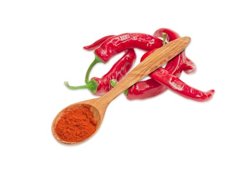 Сhili powder in a wooden spoon and several fresh red peppers chili on a light background
