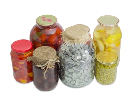 Coins of the Ukrainian hryvnia in big glass jar for home canning among canned fruit and canned vegetable on a light background
