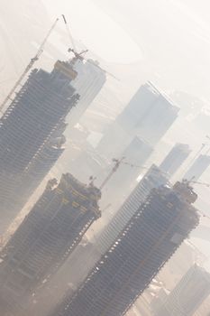 Huge skyscrappers construction site with cranes on top of buildings. Rapid urban and construction sector development or inflation of real estate bubble.