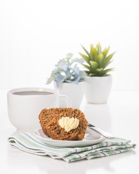 Fresh bran muffin and butter served with coffee.