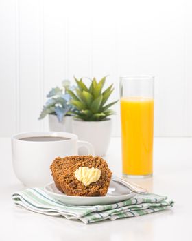 Fresh bran muffin served with coffee and orange juice.