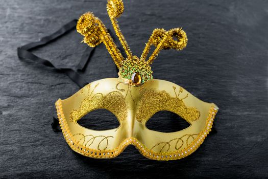 A gold Carnival mask on a black background.