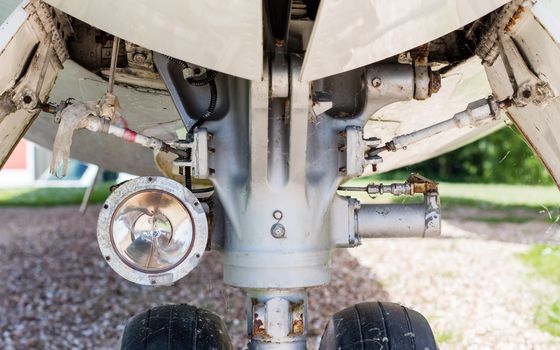 Close up aircraft nose landing gear on the tarmac with chock at the tire