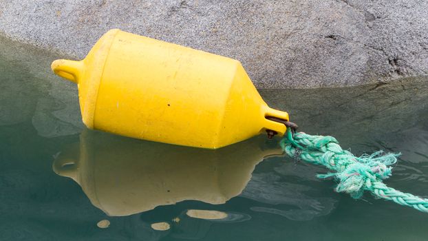 Inflatable yellow fender attached to a green rope