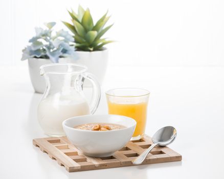 Bowl of maple walnut flavored oatmeal with a pitcher of cream.