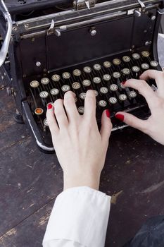 Hand of a young woman writer writing on antique typewriter