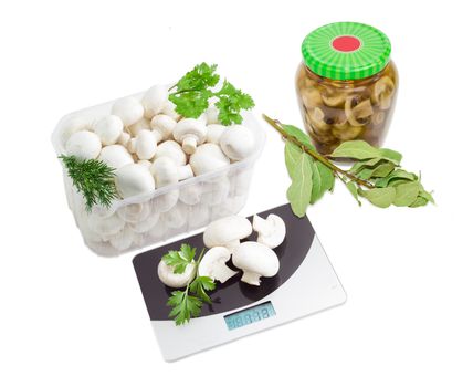 Fresh button mushrooms in a transparent plastic tray, canned mushrooms in glass jar, digital kitchen scale, branches of a dried bay leaf, fresh branches of coriander, dill and parsley on a light background
