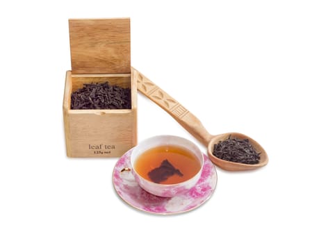 Pink saucer and cup of black tea, Large leaf of black tea in a wooden box and wooden spoon on a light background
