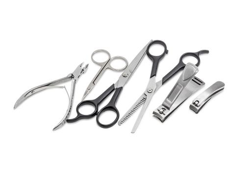 Normal hairdressers scissors and texturizing shears, nail scissors, several nail clippers different types and sizes on a light background
