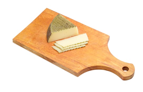 Piece and several slices of semi-hard Spanish cheese with dark coating manufactured from mixtures of cow and sheep milk on a wooden kitchen cutting board on a light background
