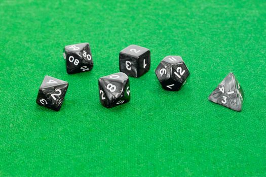 Set of specialized polyhedral dice with numbers used in role-playing games on a table with green cloth
