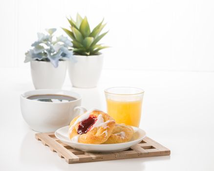 Raspberry danish served with coffee and orange juice in a breakfast setting.